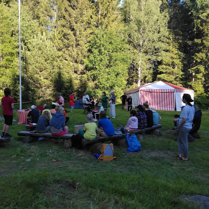 Lapsia kesäleirillä luonnossa. Taustalla raidallinen teltta.