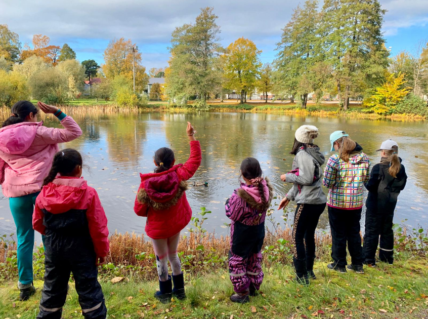 Lapsia rannalla selkä kameraan päin.
